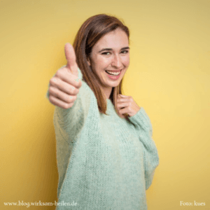 Lächelndes blondes Mädchen zeigt Daumen hoch
