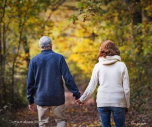 Älteres Paar geht im Herbst im Wald spazieren.