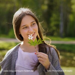 Fruehjahrskurs-mit-Schuessler-Salzen_junge-Frau-haelt-Blume