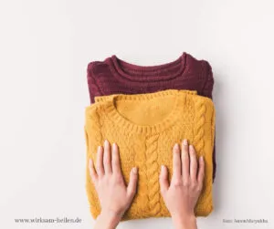 Ein gelber und roter Strickpullover liegen übereinander gestapelt.