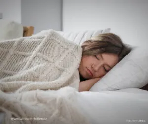 Junge Frau schläft mit Wolldecke.