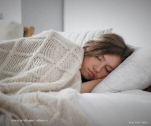Junge Frau schläft mit Wolldecke.